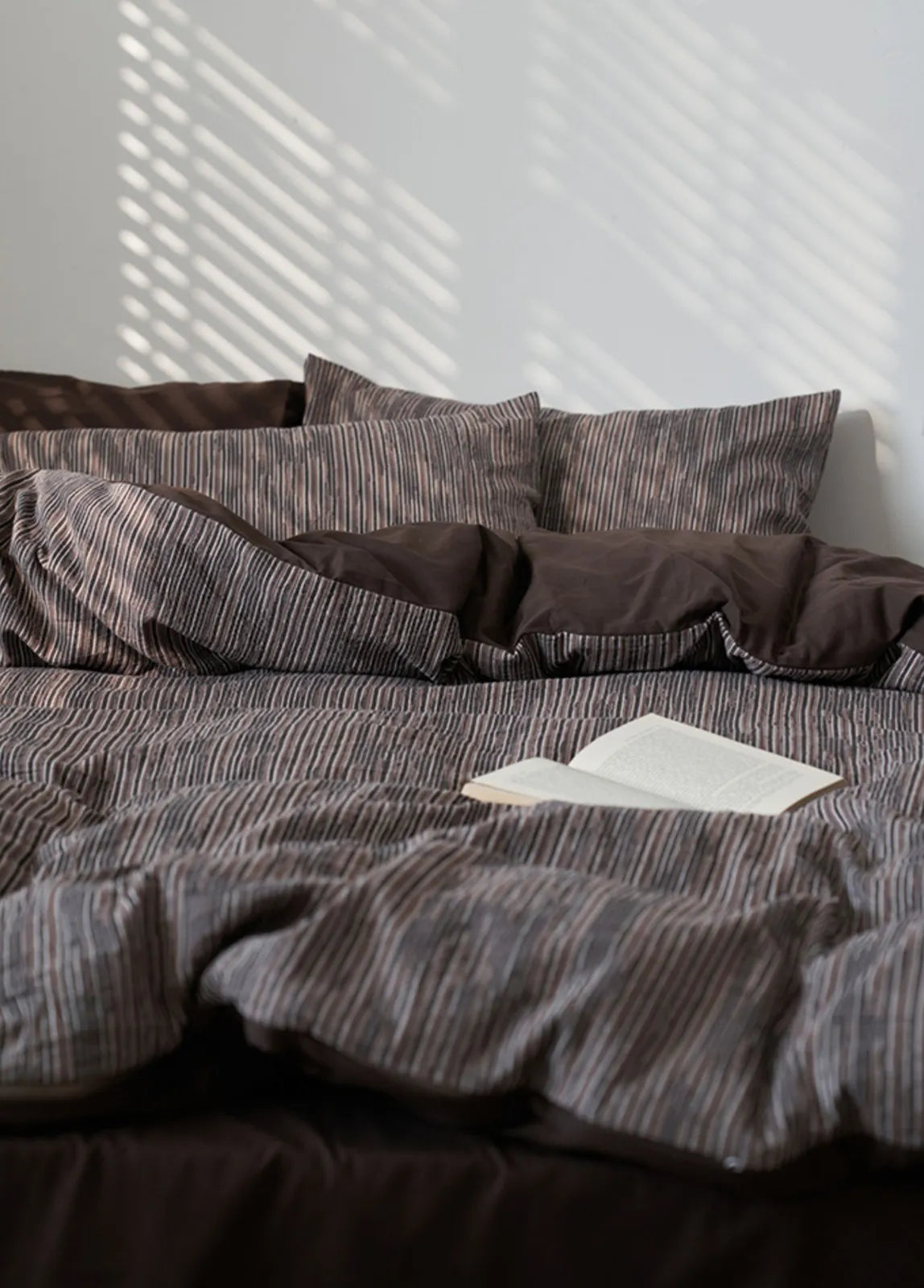 Mocha Brown Pinstripe Washed Cotton Bedding Set with sunlight casting shadows from blinds - RoomDen