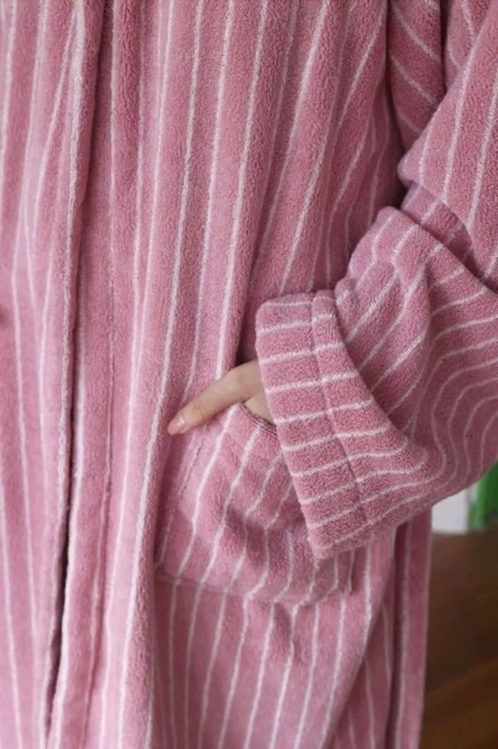 Detail shot of the hand inside the spacious pocket of the pink striped bathrobe - RoomDen