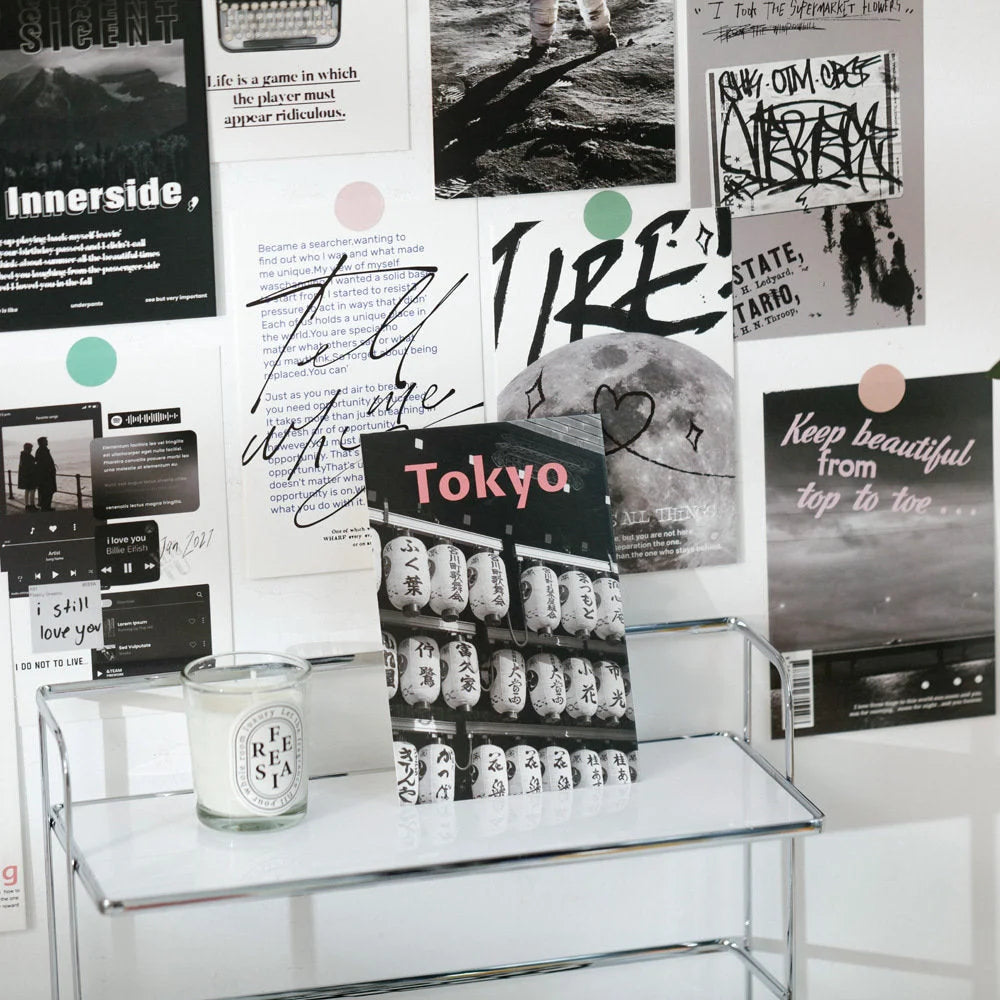 A "Tokyo" themed card from the monochrome poster set displayed on a metal shelf next to a scented candle - RoomDen.