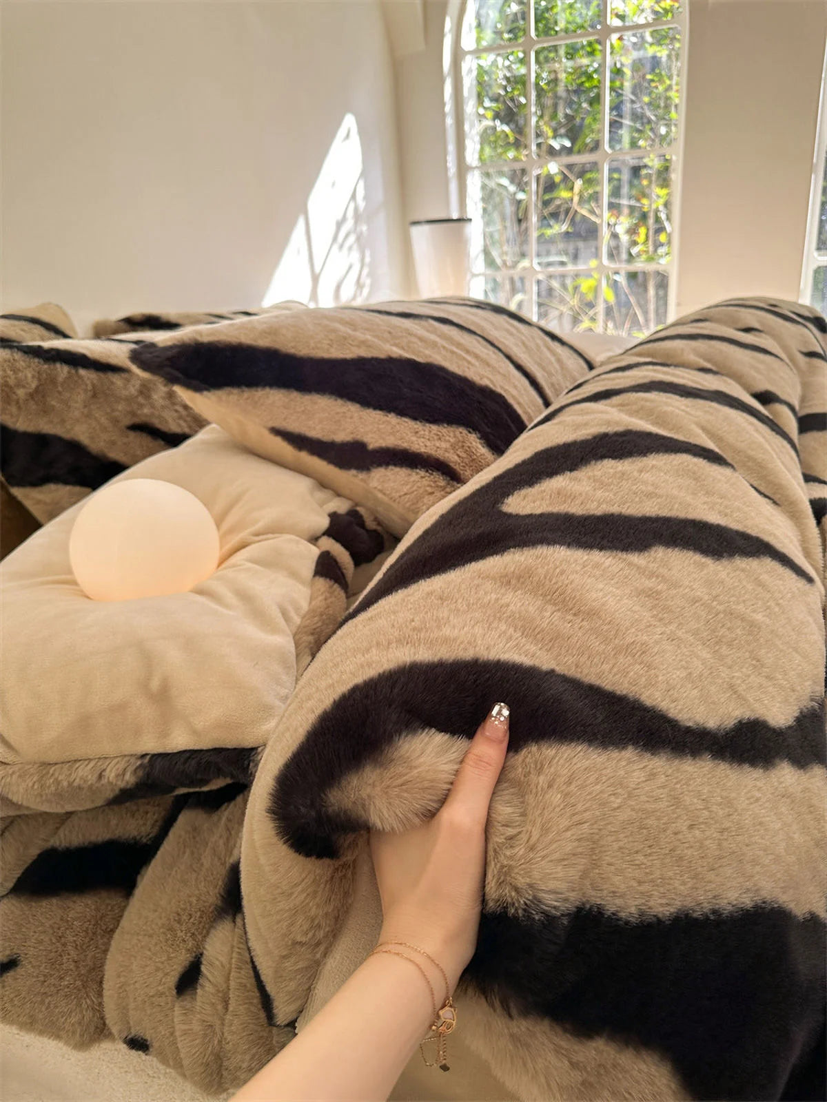 A close-up detail shot showing a hand touching the incredibly soft and fuzzy texture of the Mocha Brown tiger stripe duvet cover. - RoomDen