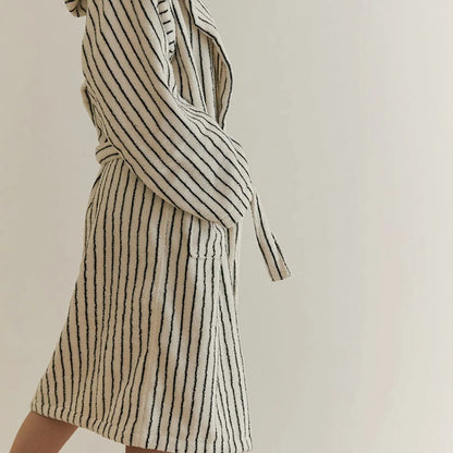 Side standing view showing the length and relaxed fit of the cream striped cotton bathrobe.
