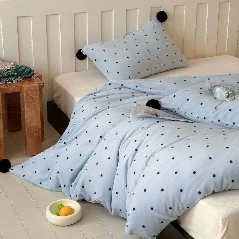 A cozy bedroom scene featuring the Baby Blue Polka Dot Pom Pom Velvet Bedding Set on a bed with a white headboard. - RoomDen