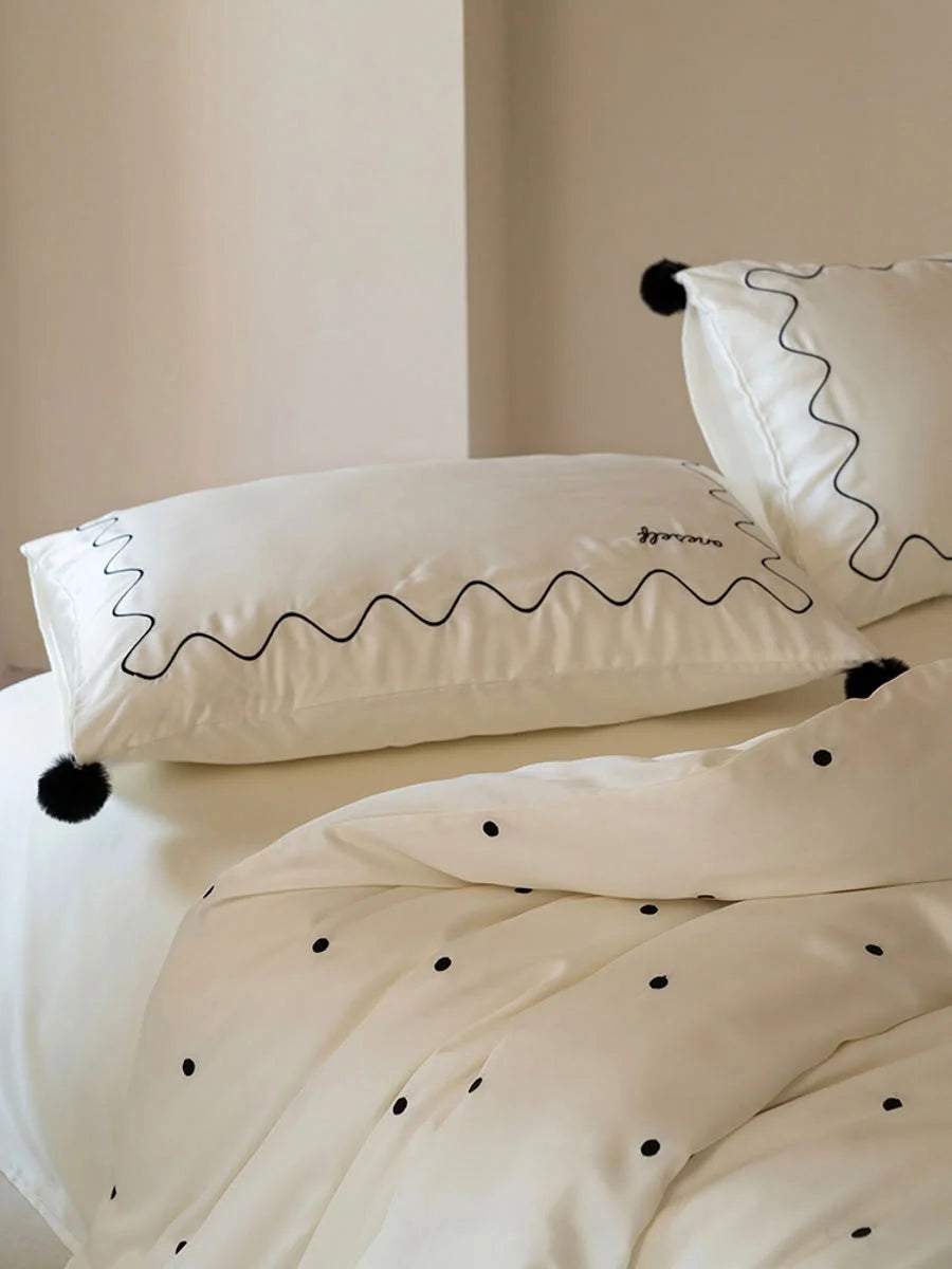 Close-up on the pillowcase of the Creamy White & Black Tencel set, showing the "oneself" embroidery and pom pom. - RoomDen