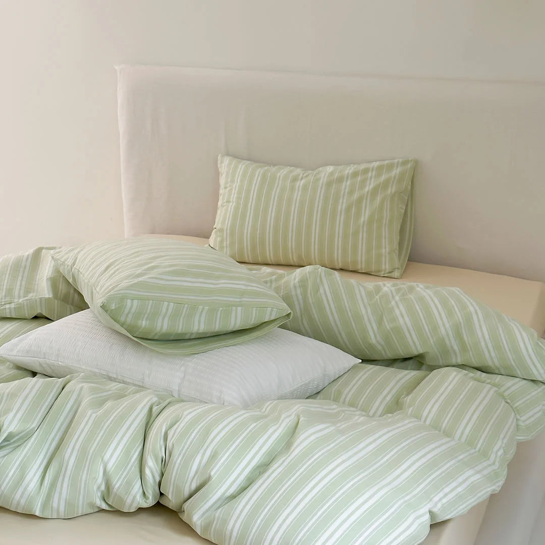 Cozy Pile of Sage Green Striped Bedding and White Pillows - RoomDen