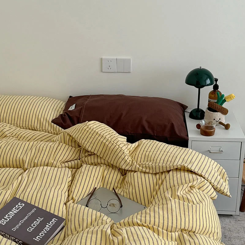 Yellow & Brown Striped Washed Cotton Bedding Set on a bed, styled with a dark green lamp on a white nightstand - RoomDen.