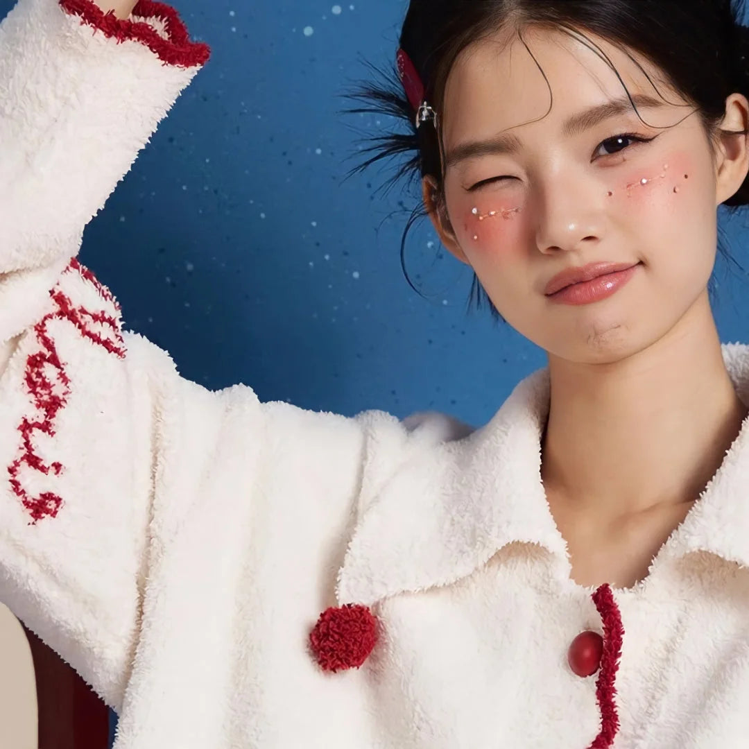 Close-up detail of the collar, red pom-pom, and embroidered sleeve of the fleece pajama top.