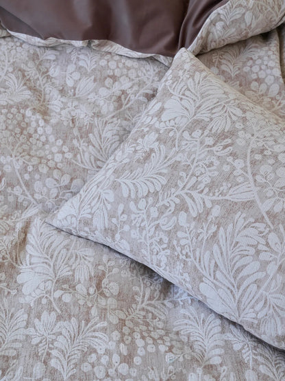 Detailed shot of the corner of a pillowcase, highlighting the intricate white and brown floral and berry pattern on the textured washed cotton fabric. - RoomDen