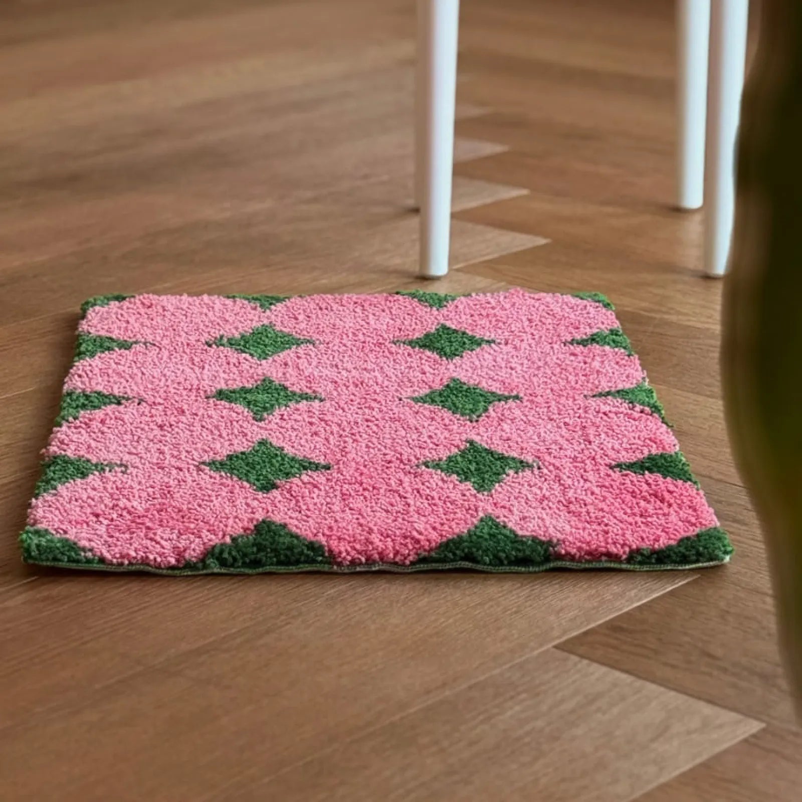 Side angle view of plush pink and green tufted rug - RoomDen