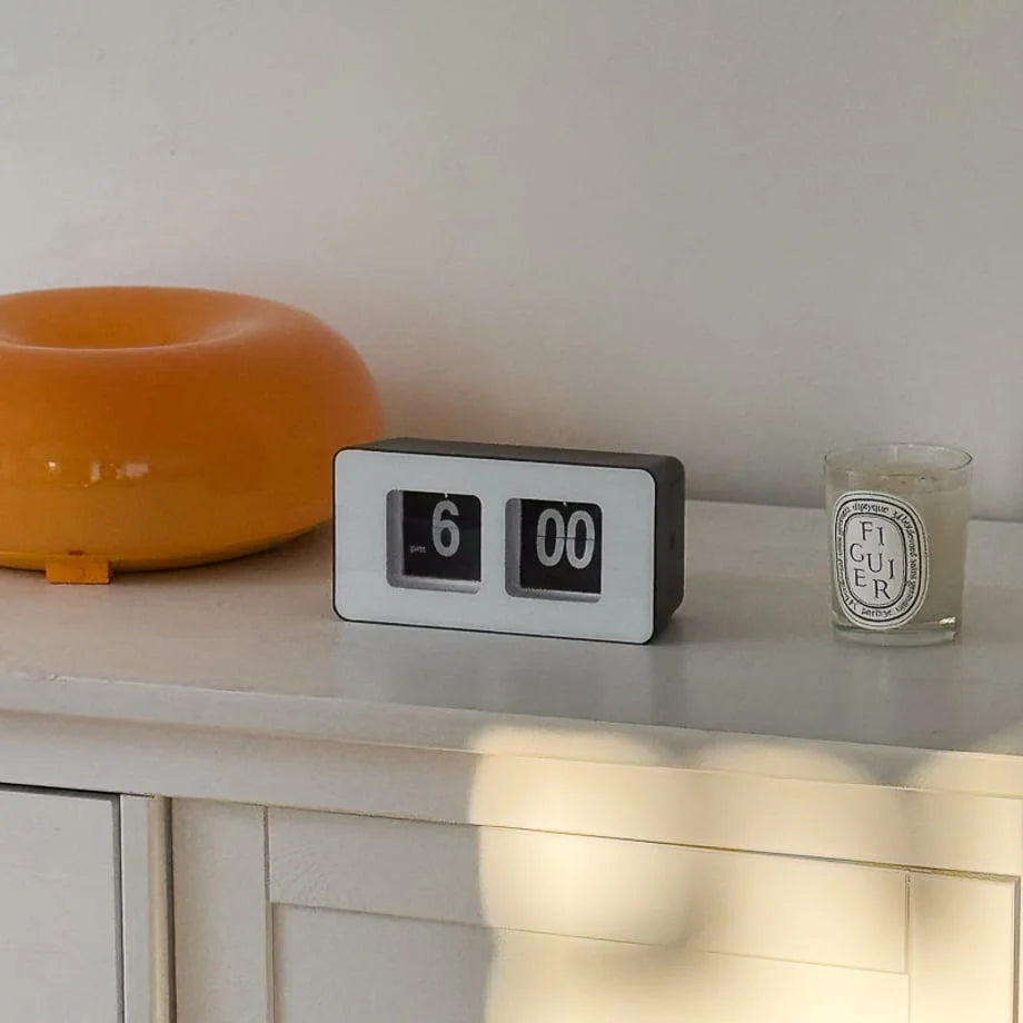 Angled view of the black and white flip clock on a white surface, showing 6:00 PM. - RoomDen