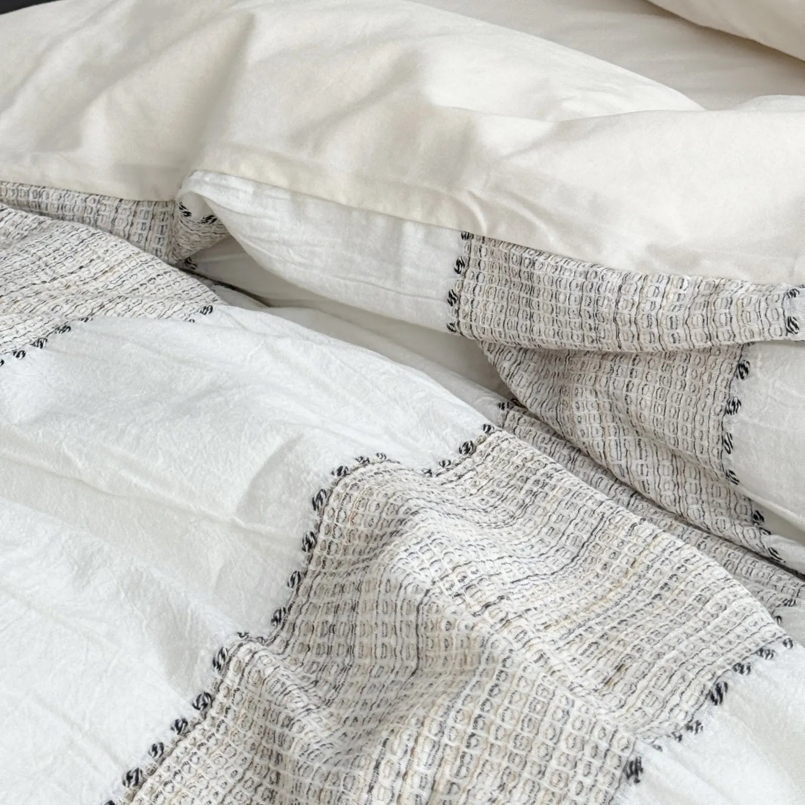 Macro shot showing the embroidered edges and woven texture of the Oatmeal Beige striped bedding.