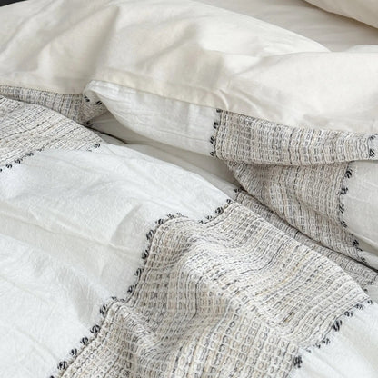 Macro shot showing the embroidered edges and woven texture of the Oatmeal Beige striped bedding.
