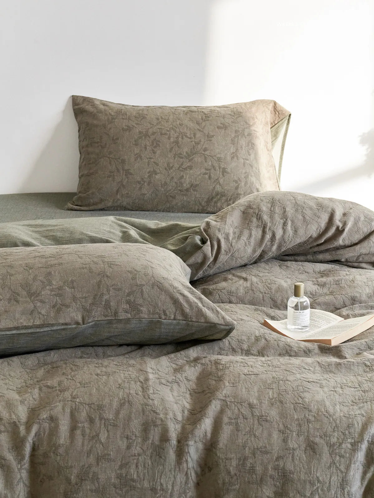 Close-up of Textured Botanical Washed Cotton Bedding Set in an earthy green color, showing the crinkled fabric and leaf pattern - RoomDen.