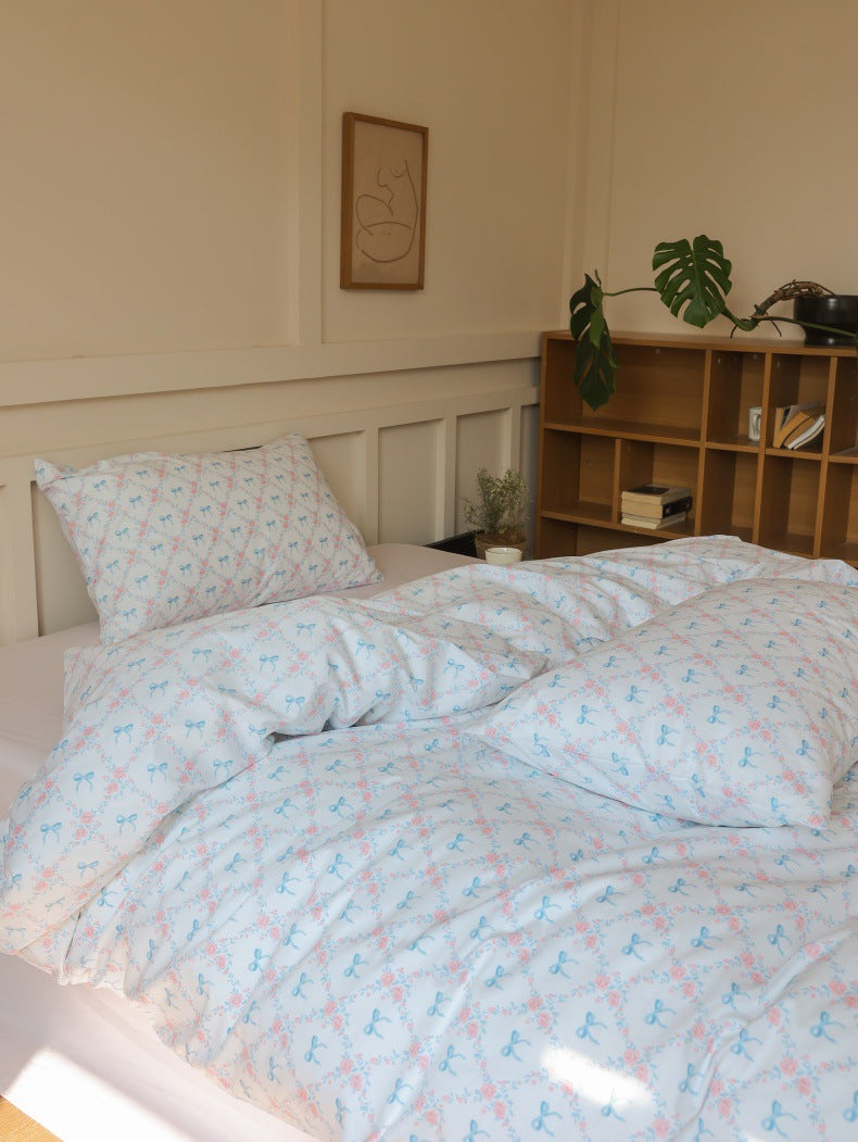 Ivory Blue Bow Rose Cotton Bedding Set – sunlit duvet and pillows beside the bookcase - Roomden