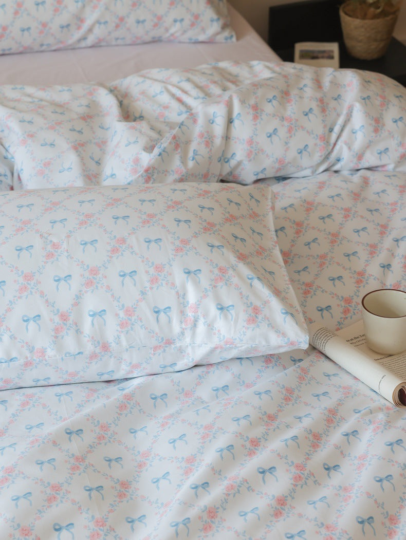 Ivory Blue Bow Rose Cotton Bedding Set – fabric pattern detail beside a bedside book - Roomden