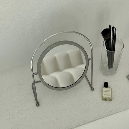 The metal makeup mirror reflecting a white sofa, showcasing its clear reflective surface. - RoomDen