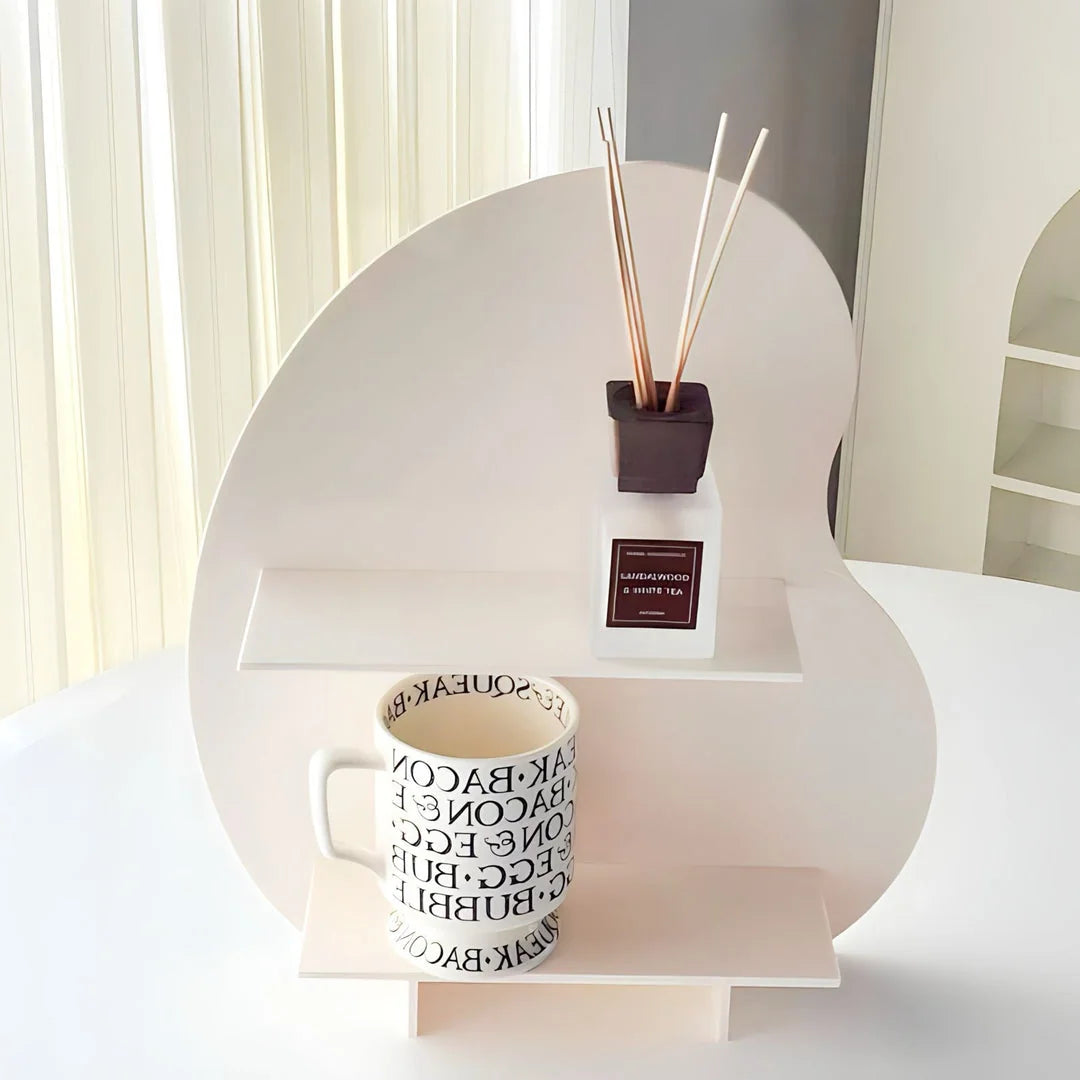 The frosted white version of the wavy desktop organizer displayed on a white table with a mug. - RoomDen