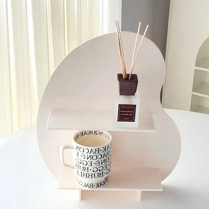 The frosted white version of the wavy desktop organizer displayed on a white table with a mug. - RoomDen