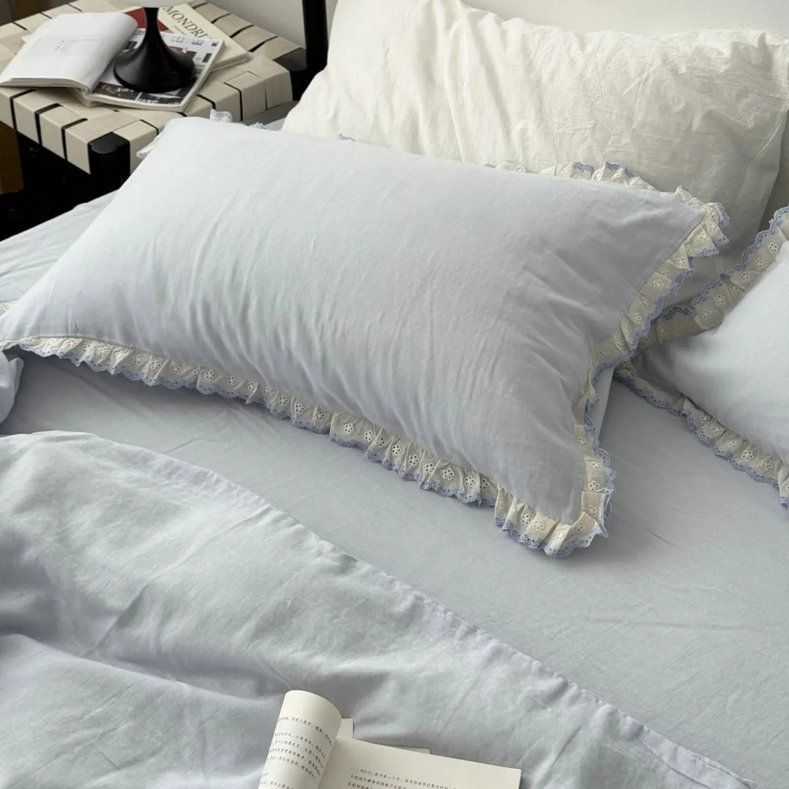 Angled view of the sky blue lace trim pillowcases and duvet cover, showing the soft texture of the washed cotton.
