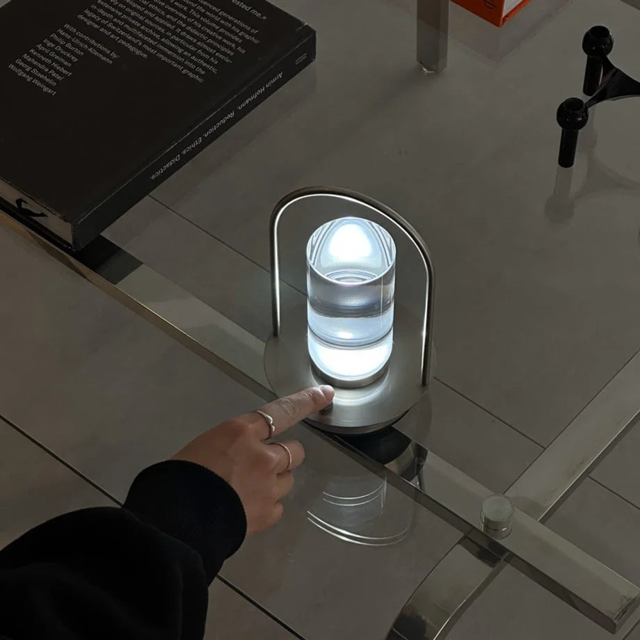 The Minimalist Arch Metal Table Lamp turned on with a cool white light. - RoomDen