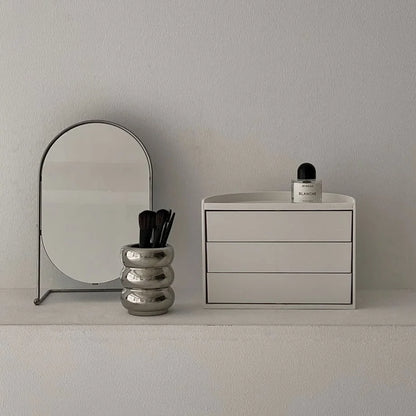 Front view of the closed Ribbed Swivel ABS Makeup Organizer on a white vanity shelf. - RoomDen