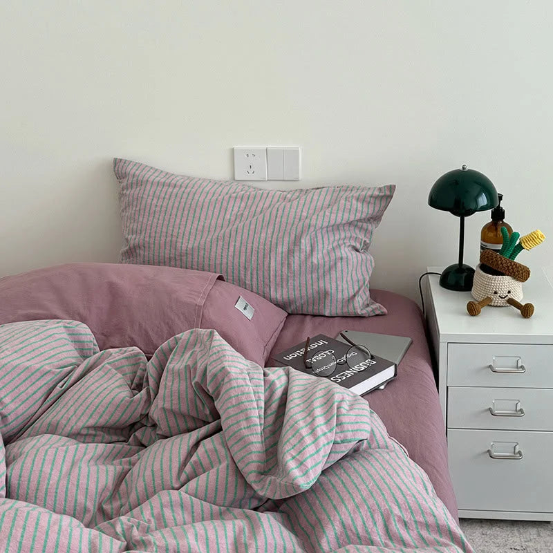 Pink & Green Striped Washed Cotton Bedding Set styled with a solid mauve pillow and a dark green lamp on the nightstand - RoomDen.