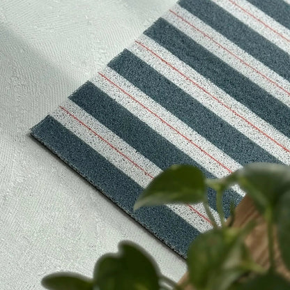Green and white striped PVC coil rug with red pinstripe details on concrete floor - RoomDen