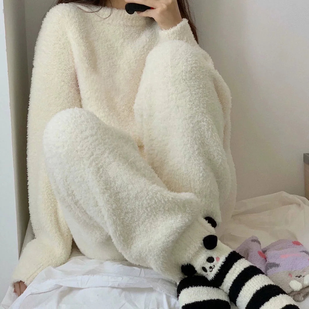 A woman sitting on a bed wearing the plush Cream White Flannel Fleece Pajama Set - RoomDen