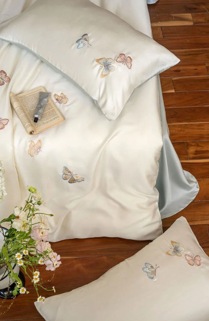 Overhead detail shot of a pillow and duvet cover, showcasing the intricate butterfly embroidery.