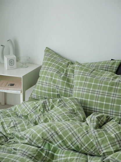 The green plaid bedding set in a serene bedroom setting, emphasizing its calming and cozy aesthetic next to a modern white nightstand. - RoomDen