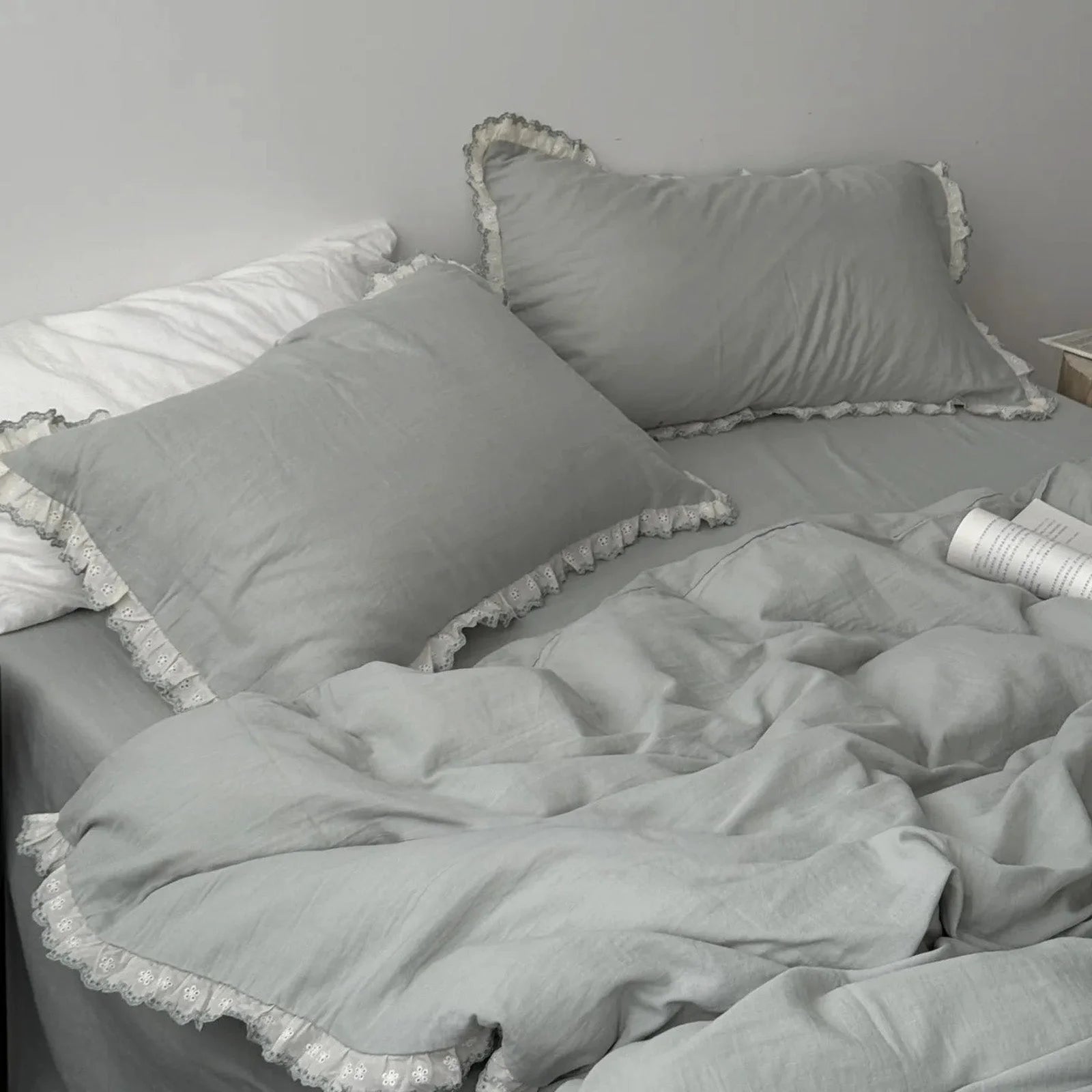 Sage green lace ruffle bedding set on a bed, with soft, natural lighting enhancing its cozy texture.