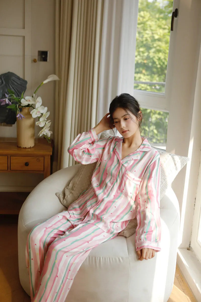 Woman sitting in Coquette style pink striped pajamas with heart details