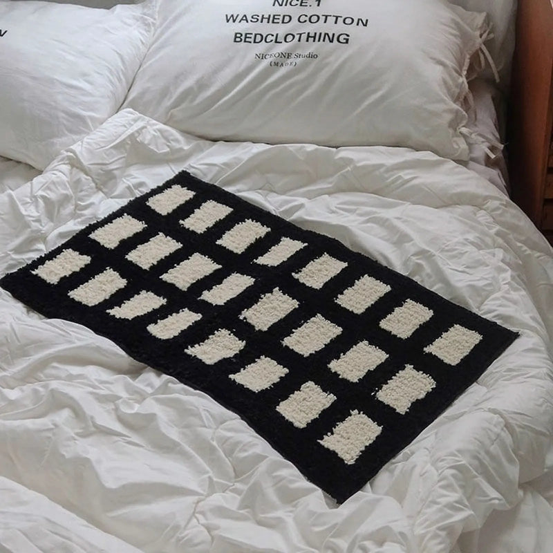 Small black geometric tufted rug styled for a moody bedroom corner - RoomDen