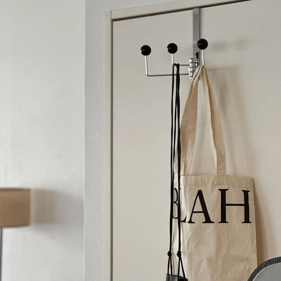 Angled lifestyle view of the black over-the-door hook, showing its placement in a room setting - RoomDen