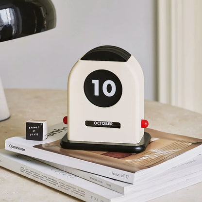 Close-up of the Cream & Black Retro Wooden Perpetual Desk Calendar on an Openhouse magazine - RoomDen