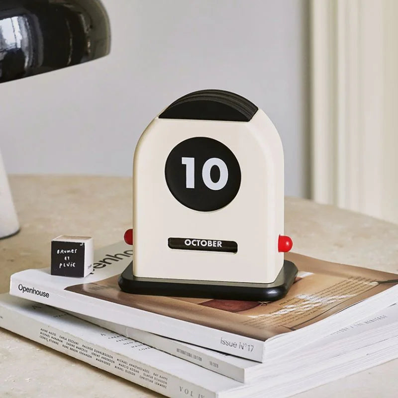 Close-up of the Cream & Black Retro Wooden Perpetual Desk Calendar on an Openhouse magazine - RoomDen