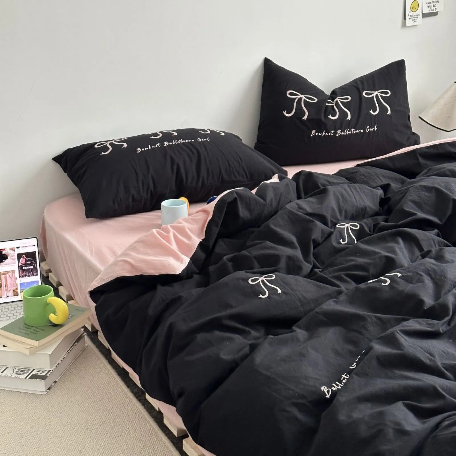 The black embroidered bowknot bedding set styled on a bed with a pink fitted sheet, creating a cute, contrasting aesthetic.