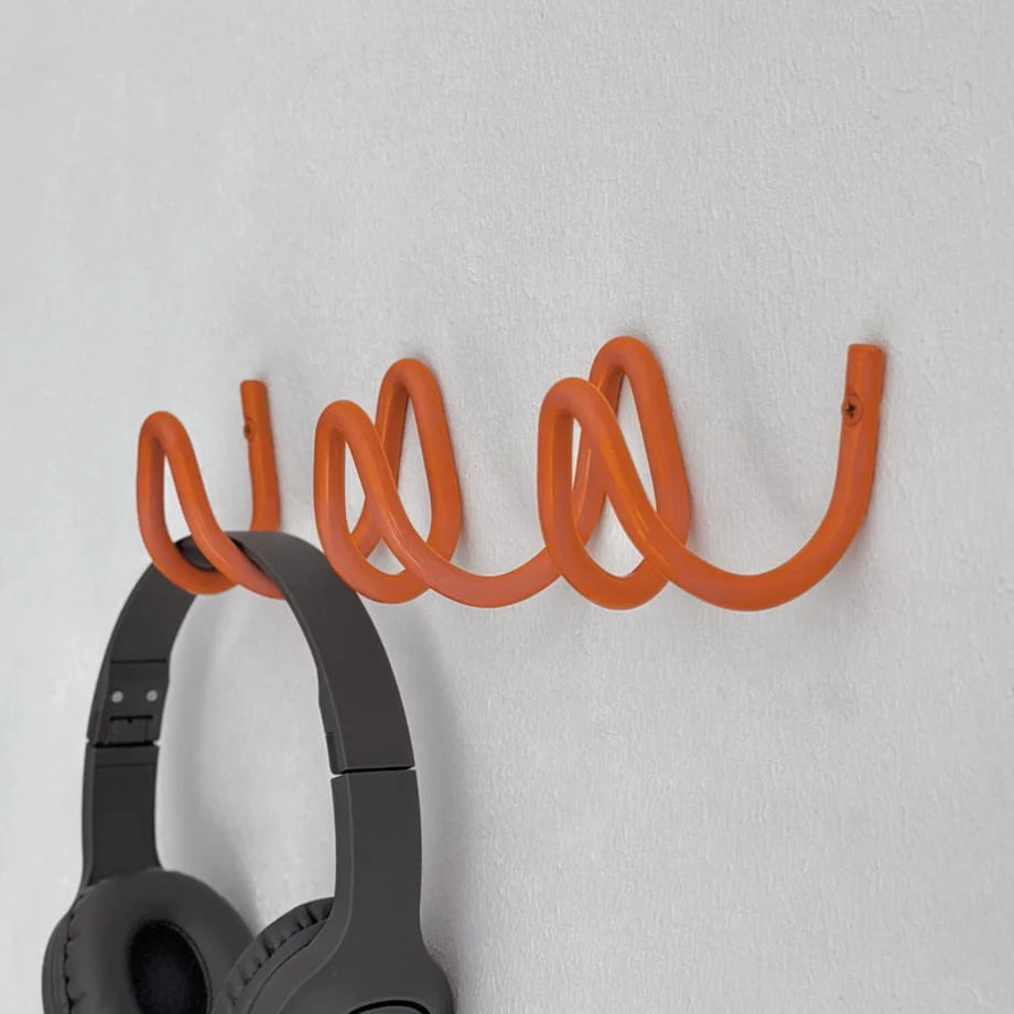 Detail shot showing the smooth, coiled texture of the orange metal wall hook. - RoomDen