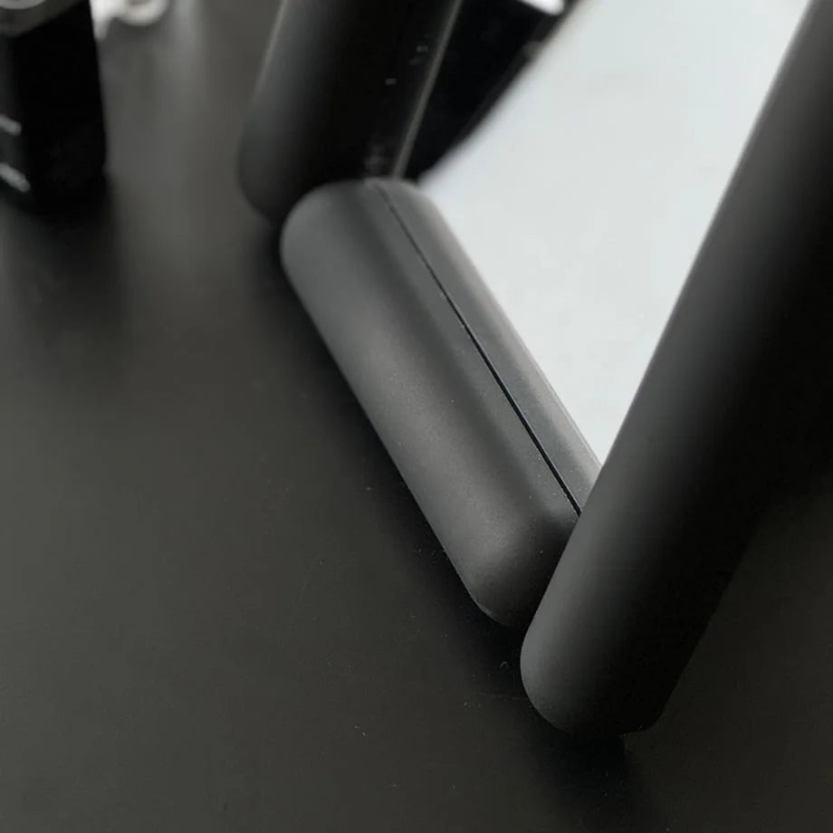Close-up on the matte texture of the black mirror's pill-shaped frame. - RoomDen