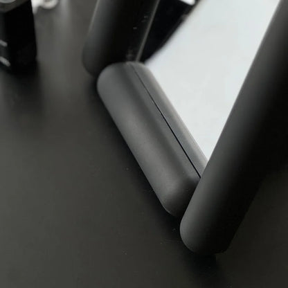 Close-up on the matte texture of the black mirror's pill-shaped frame. - RoomDen