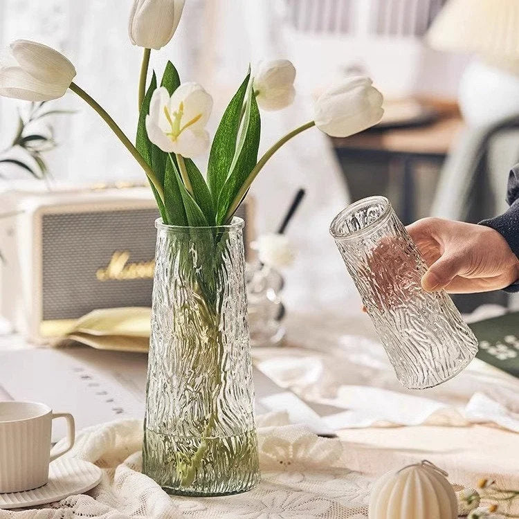 Hand holding the Large Bark Textured Glass Vase next to the Large Ribbed Glass Vase holding white tulips. - RoomDen