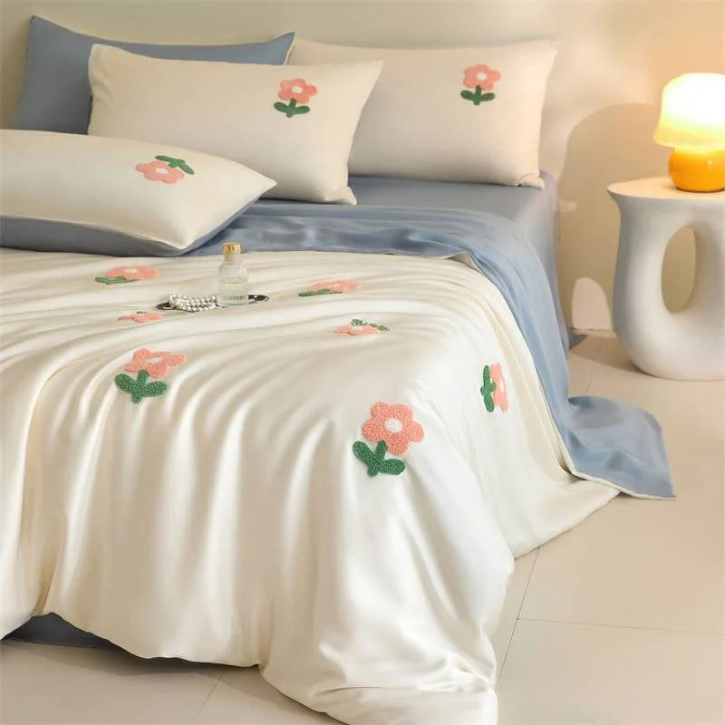 Close-up shot of the white duvet cover with pink tufted flowers and the silky sky blue sheet. - RoomDen
