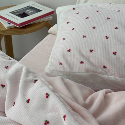 Close-up of the cherry print pillowcase, showing the soft texture next to a wooden side table with books. - RoomDen