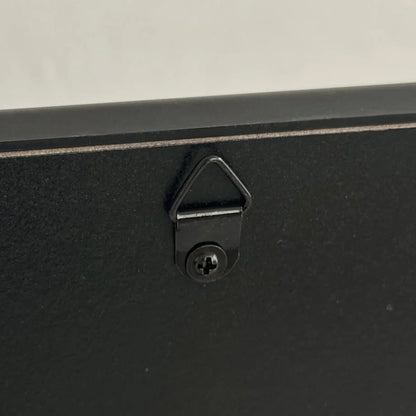 Close-up of the sawtooth hanger on the back of the black wall mirror. - RoomDen