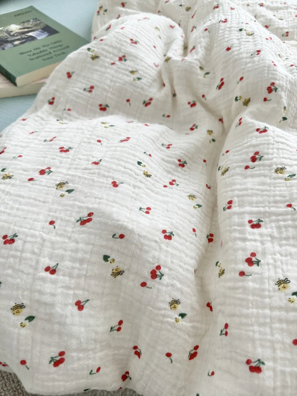 Close-up shot showing the soft, crinkled fabric and the whimsical cherry and bee pattern of the duvet cover. - RoomDen