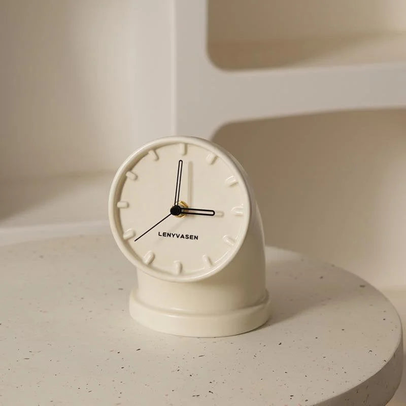 Cream white Industrial Pipe Ceramic Table Clock with black hands, shown on a textured white surface - RoomDen