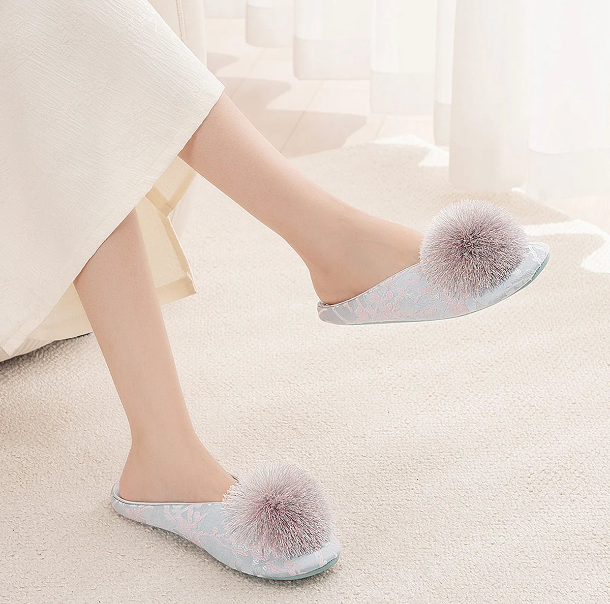 Woman wearing blue cotton sateen slippers with floral pattern and pom-pom - RoomDen