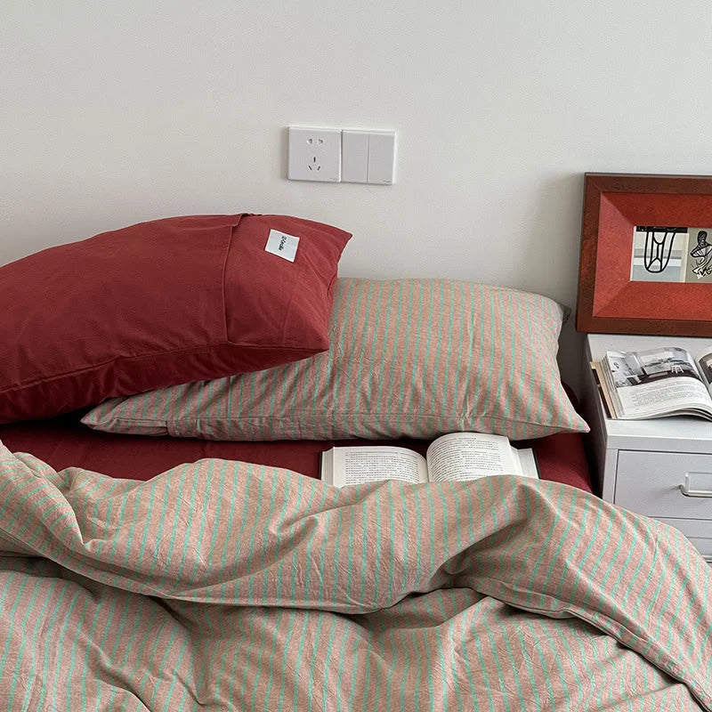 Angled view of the Red & Green Striped Washed Cotton Bedding Set, highlighting the pillowcases and an open book - RoomDen.