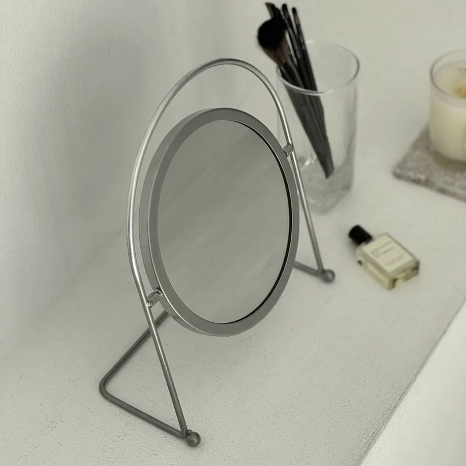 A high-angle shot highlighting the sleek, circular frame of the grey desktop mirror. - RoomDen