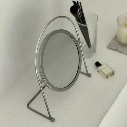 A high-angle shot highlighting the sleek, circular frame of the grey desktop mirror. - RoomDen