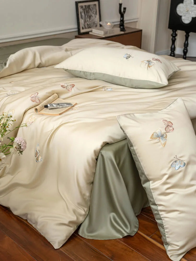 Angled shot of the beige duvet cover with butterfly embroidery, showing the sage green sheet underneath - RoomDen